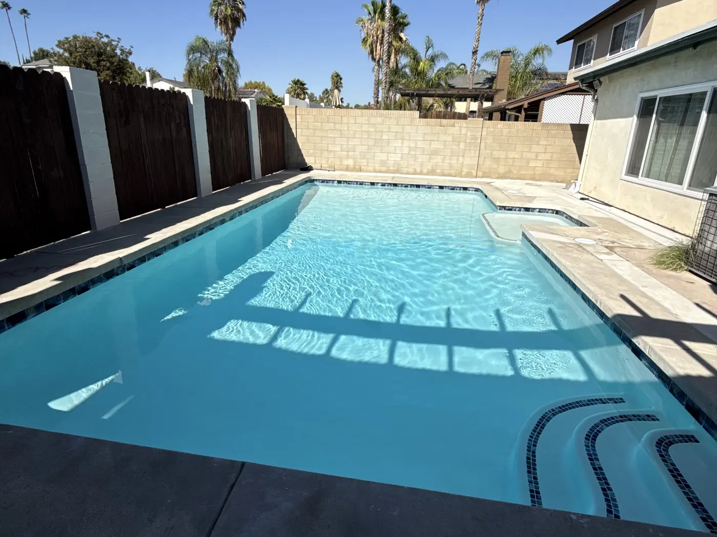 Clean, well-maintained backyard swimming pool with blue tile accents in Santa Clarita