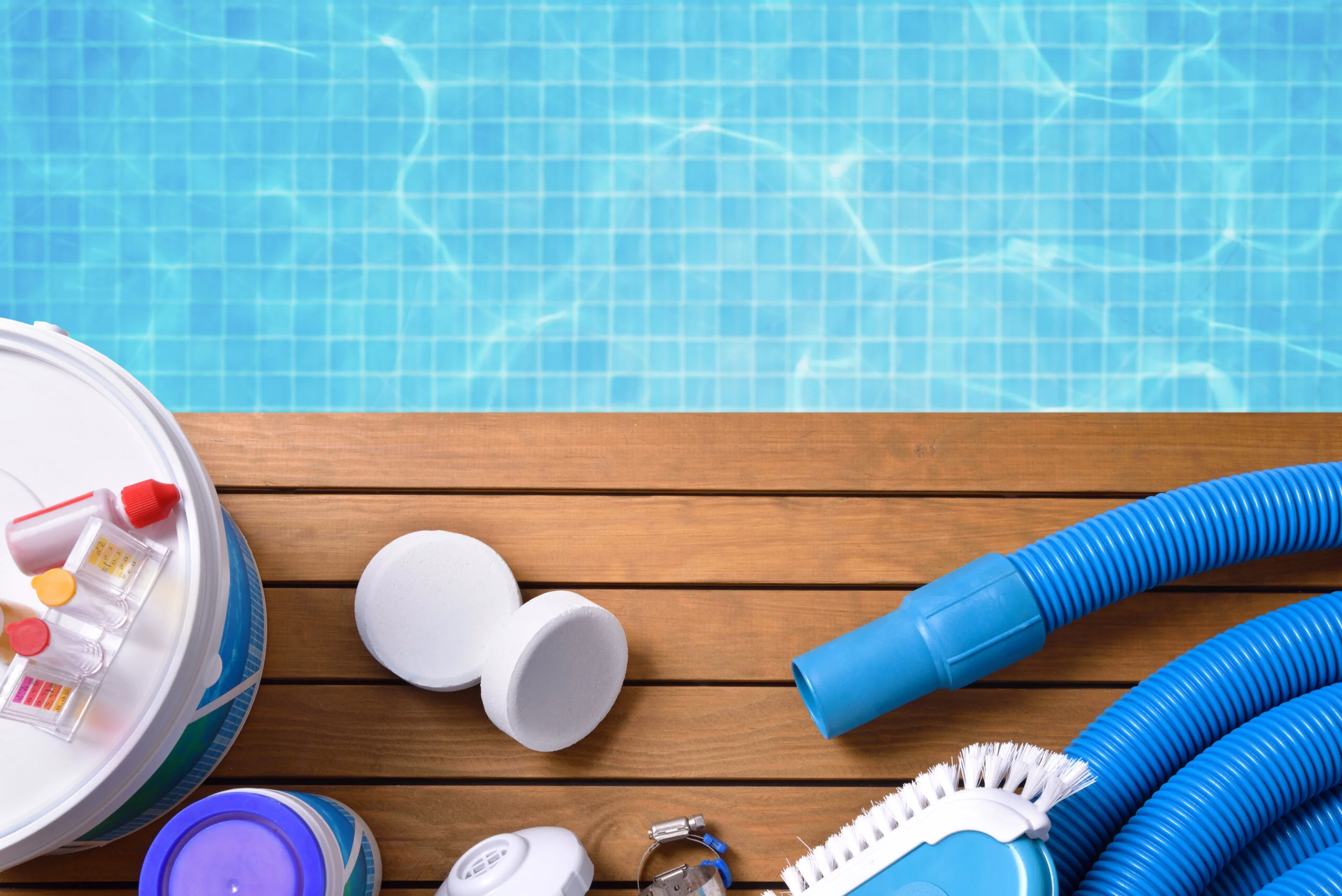 Pool cleaning chemicals and tools on a wooden pool deck