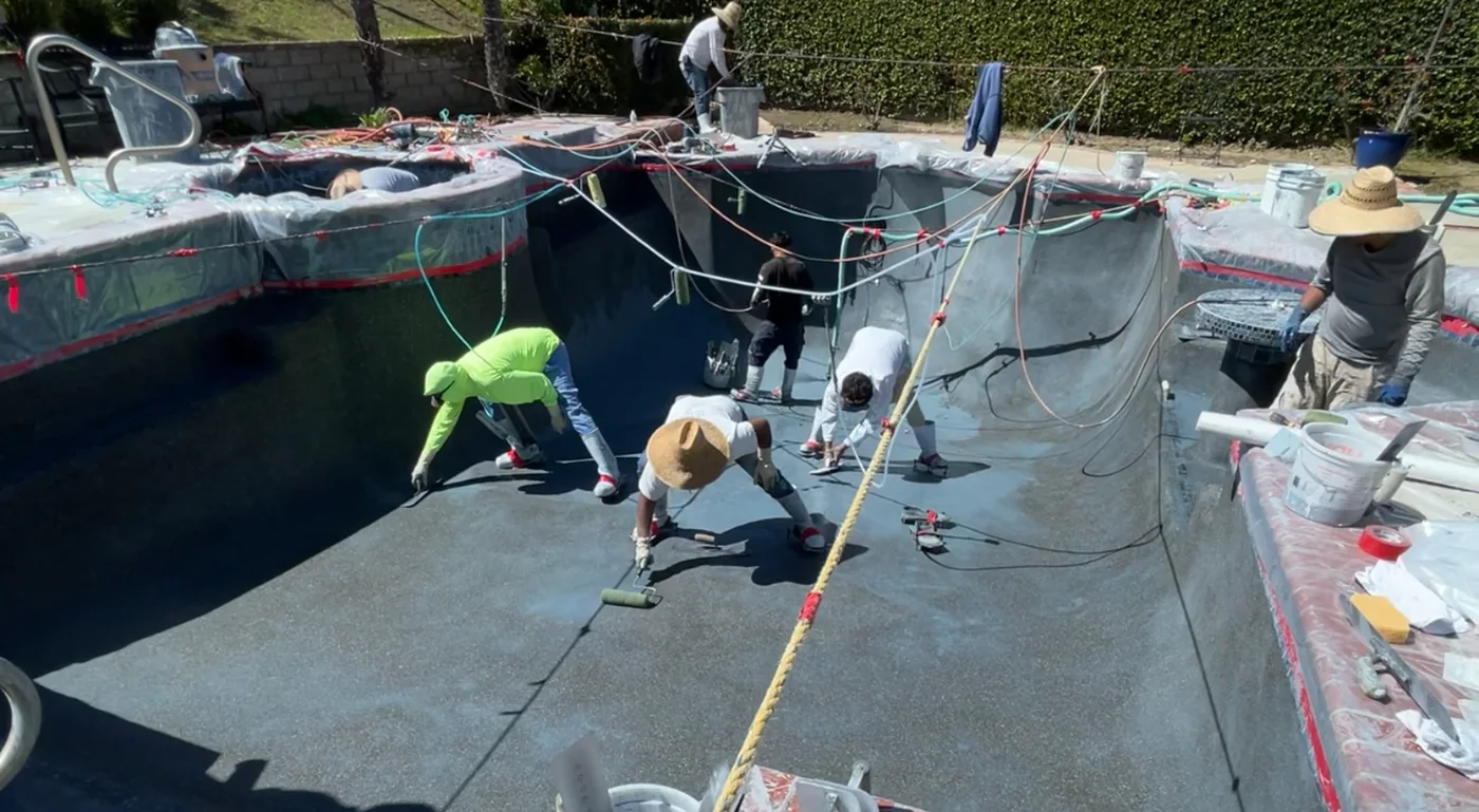 GK Swimming Pools crew applying a dark plaster finish during a pool remodel